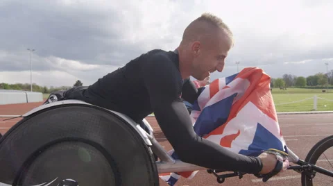 4K Winning disabled athlete at racing event doing victory lap with British flag. Stock Footage 64623997
