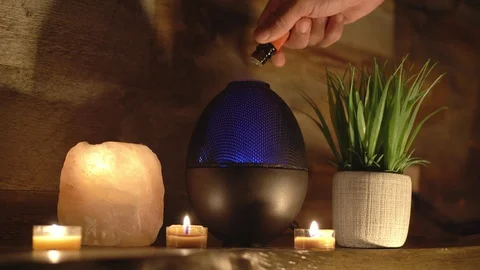 4k, Woman adding essential oil to electric diffuser lamp, candles on table Stock Footage 129299073