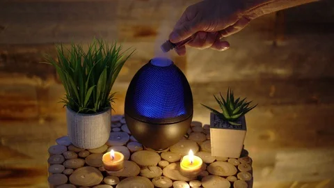 4k, Woman adding essential oil to electric diffuser lamp, candles on table Stock Footage 129299210