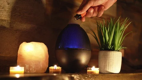 4k, Woman adding essential oil to electric diffuser lamp, candles on table Stock Footage 129299286