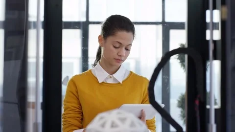 4K Woman looking at prototype in 3D printer &amp; checking design on tablet computer Stock Footage 73823954