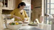 4K Woman Preparing Meal In Kitchen At Home, Following Recipe On Computer Tablet Stock Footage