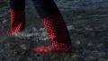 4K woman in red boots are walking in the water at the shoreline on pebble beach 4k or 4k+ Resolution