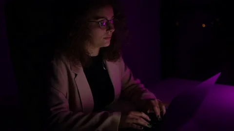 4K, Woman in suit using computer in the dark of night. There are colors lights. Stock Footage 147850840
