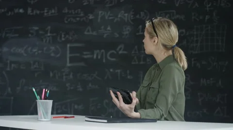 4K Woman using tablet in classroom, blackboard with math formulas in background Stock Footage 67879050