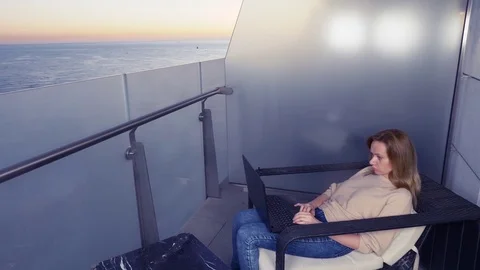 4k. woman working on a laptop computer on the balcony of a resort hotel with sea Stock Footage 83145271