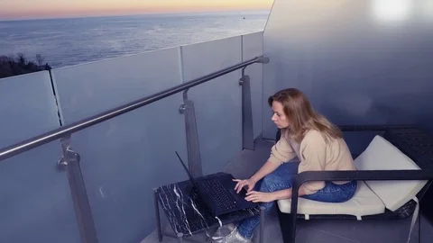 4k. woman working on a laptop computer on the balcony of a resort hotel with sea Stock Footage 83145485