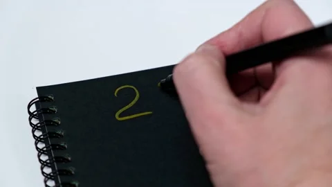 4K A woman's hand writes 2022 with a gold felt-tip pen in a black notebook. Stock Footage 166488480