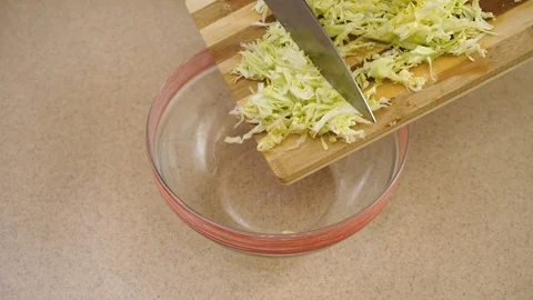 4k. Woman’s hands are adding the cabbage from a board into a glass plate Stock Footage 128329197