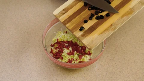 4k.  Woman’s hands are adding the olives from a  board into a glass plate Stock Footage 128329209