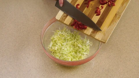 4k. Woman’s hands are adding the red pepper from a board into a glass plate. Stock Footage 128329217