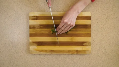 4K.  Woman’s hands are cutting the dill on a kitchen board Stock Footage 128329152