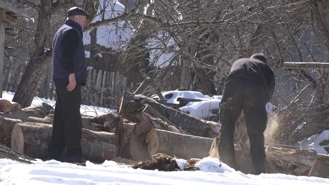 4K Worker man sawing tree trunk in winter day mountain farm yard chainsaw tool Stock Footage 80068124