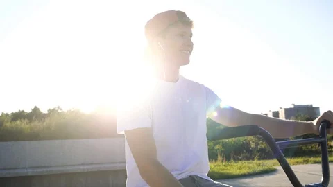 4K Young active man smiling and listening to music on headphones on BMX Stock Footage 117725418