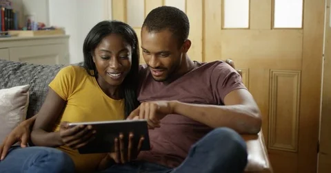4K Young affectionate couple at home looking at digital tablet &amp; discussing Video stock 82296617