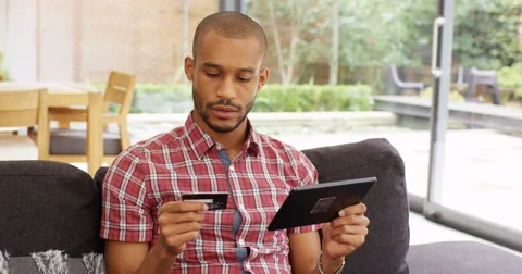 4k, Young African American man using his credit card to make an online purchase  Stock Footage