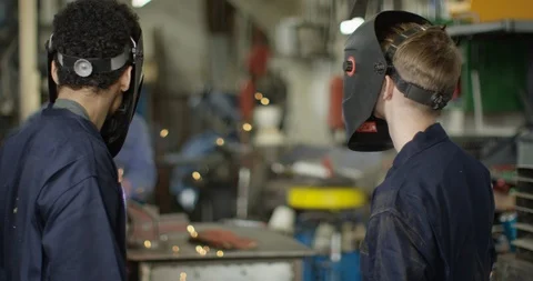 4K Young apprentice welders lifting visors &amp; smiling at camera in workshop Video stock 111662454