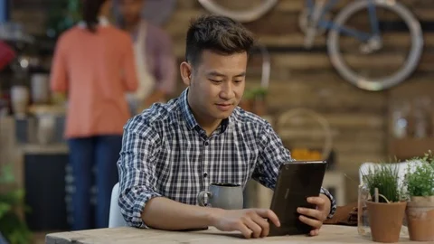 4K Young casual man having a video chat on tablet in trendy city coffee shop Stock Footage 76539598