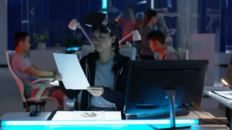4K Young computer game designer working at her desk &amp; looking into VR viewer Stock Footage 67495256