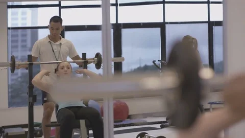 4K Young group working out in the gym, trainer spotting for girl lifting weights Video stock 75861383