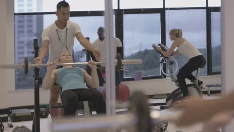 4K Young group working out in the gym, trainer spotting for girl lifting weights Video stock 75861455