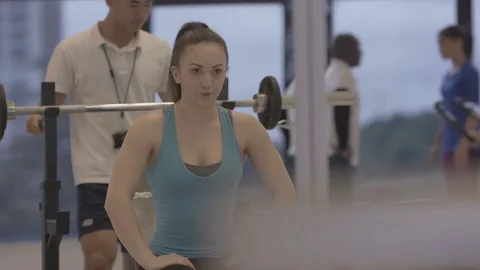 4K Young group working out in the gym, trainer spotting for girl lifting weights Video stock 75861999