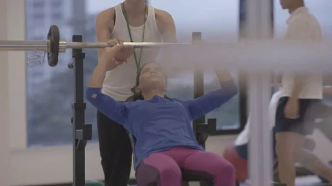 4K Young group working out in the gym, trainer spotting for girl lifting weights Video stock 75862922