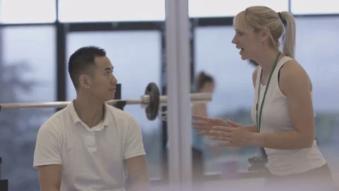 4K Young group working out in the gym, trainer spotting for guy lifting weights Video stock 75863256