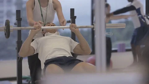 4K Young group working out in the gym, trainer spotting for guy lifting weights Video stock 75863322