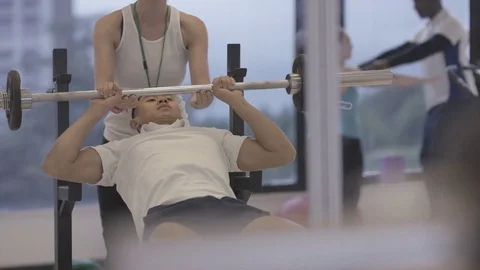 4K Young group working out in the gym, trainer spotting for guy lifting weights Video stock 75863539