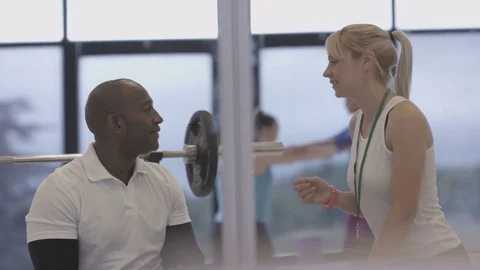 4K Young group working out in the gym, trainer spotting for guy lifting weights Video stock 75863596