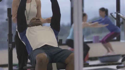 4K Young group working out in the gym, trainer spotting for guy lifting weights Video stock 75863941