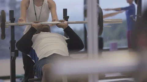 4K Young group working out in the gym, trainer spotting for guy lifting weights Stock Footage 75863966