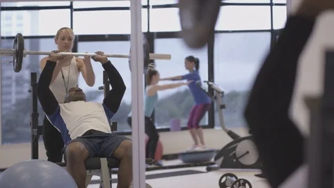 4K Young group working out in the gym, trainer spotting for guy lifting weights Video stock 75864643