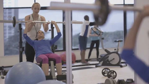 4K Young group working out in the gym, trainer spotting for girl lifting weights Stock Footage 75865404