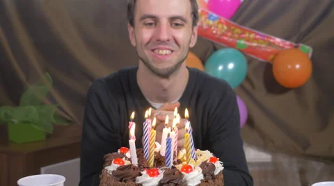 4k - Young handsome man blowing candles on a birthday cake Stock Footage 48349095