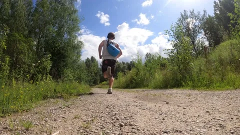 4K young man running/jogging away with a sack in a sunny summers day Stock Footage 157013162