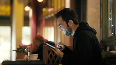 4K Young man sitting in night cafe/bistro browsing internet social media tablet  Stock Footage 58714564