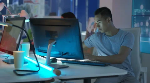 4K Young mixed ethnicity computer game design team working in dark office Video stock 67899219