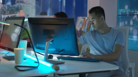 4K Young mixed ethnicity computer game design team working in dark office Video stock 67899239