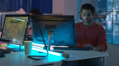 4K Young mixed ethnicity computer game design team working in dark office Video stock 67899356