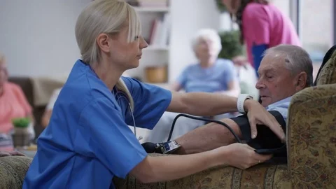 4K Young nurse checking elderly man's blood pressure in nursing home Stock Footage 73297272