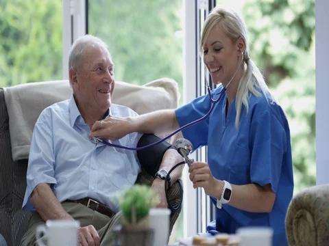 4K Young nurse checking elderly man's blood pressure in nursing home Stock Footage 73820290