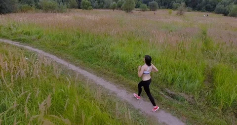 4K Young pretty girl jogging outdoors in fields and forests aerial Vídeo Stock 106553053