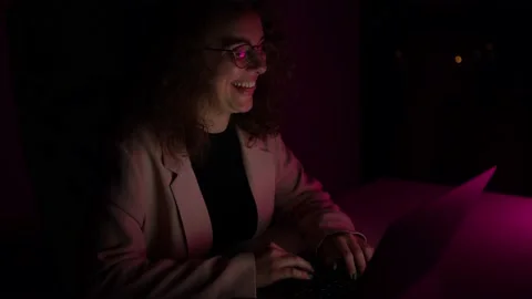 4K, Young woman typing on computer while it is night time. Colors lights. Stock Footage 147850870