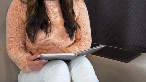 4K. Young woman writes notes in a notebook. Next to her is a laptop. Stockbeeldmateriaal 108751664