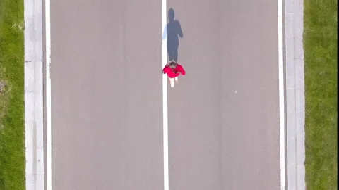  4K.Aerial. Woman runner run on empty road. Fly over woman,shadow Stockbeeldmateriaal 107323595