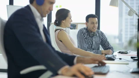 4KCheerful customer support team with headphones working at computers &amp; chatting Stock Footage 64524604
