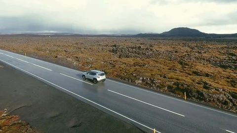 4WD off-road jeep with turned on headlights is driving up the green hill by the Stock Footage 120000008