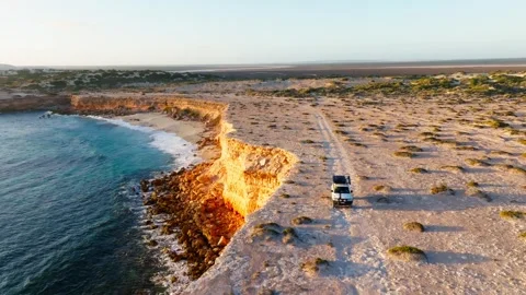 A 4x4 driving along a cliff at sunset, filmed with a drone Stock Footage 345852480